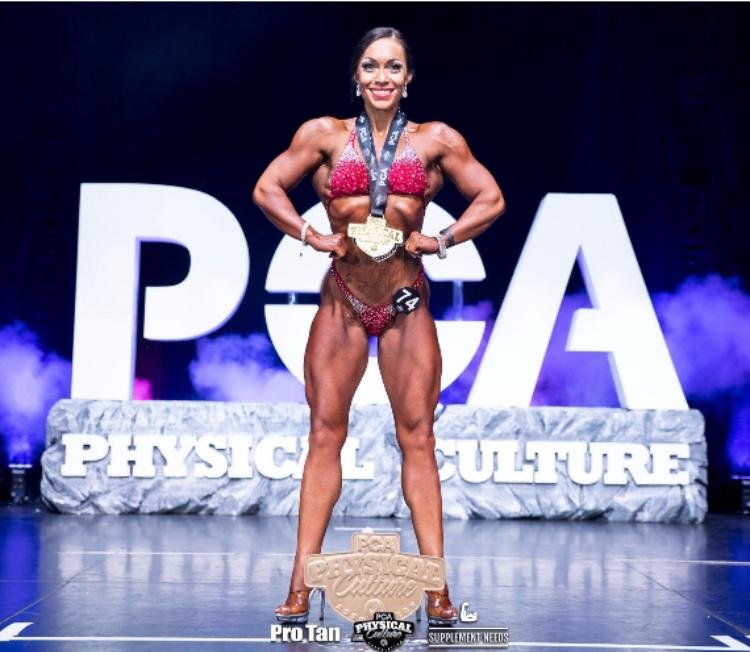 Client on stage at a bodybuilding competition, holding trophy
